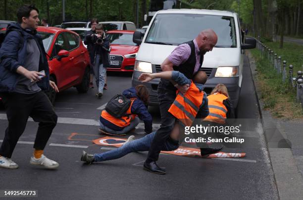 An irate motorist attempts to remove activists of the Last Generation climate action group who had blocked Puschkinallee avenue on May 23, 2023 in...