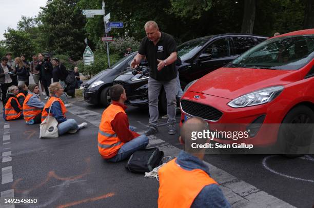 An irate motorist confronts activists of the Last Generation climate action group who had blocked Puschkinallee avenue on May 23, 2023 in Berlin,...