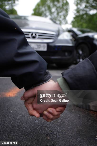 Activists of the Last Generation climate action group, their hands glued together, block Puschkinallee avenue on May 23, 2023 in Berlin, Germany....