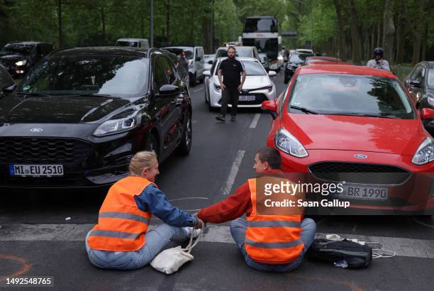 Activists of the Last Generation climate action group, their hands glued together, block Puschkinallee avenue on May 23, 2023 in Berlin, Germany....