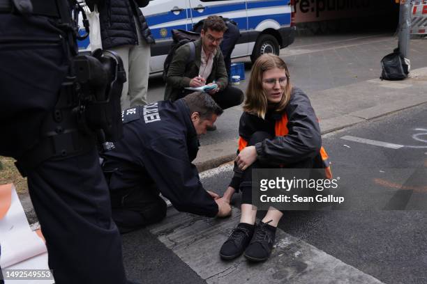 Policeman uses a solvent to unglue the hand of an activist of the Last Generation climate action group who, along with others, had blocked...