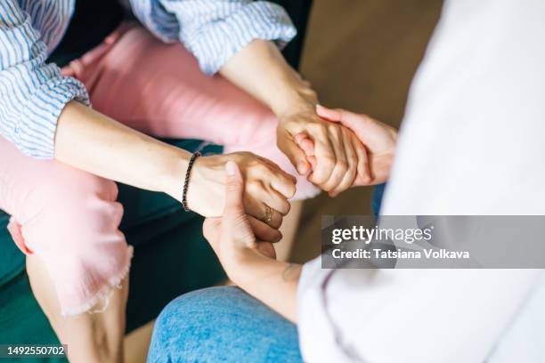 two mature caucasian woman holding hands during therapy session - empathetic listening stock pictures, royalty-free photos & images