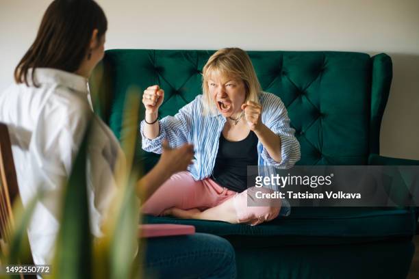 mental health professional sitting on chair looking at female patient sitting on couch with arms raised while emotionally talking about feelings - psychiatrists couch fotografías e imágenes de stock