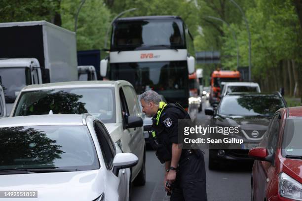 Policeman speaks with motorists stuck in traffic due to a blockade by activists from the Last Generation climate action group on Puschkinallee avenue...