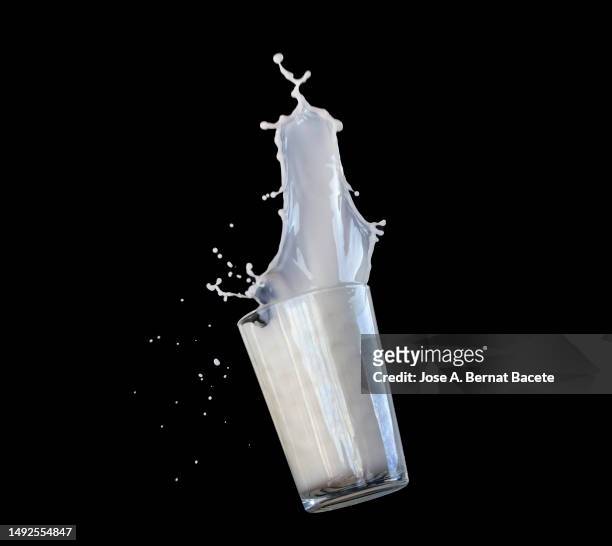 impact of a glass of milk falling to the ground on a black background. - glass of milk stock pictures, royalty-free photos & images