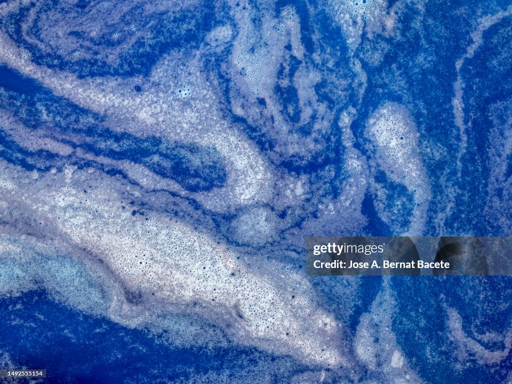 Abstract background, blue and white liquids mix.