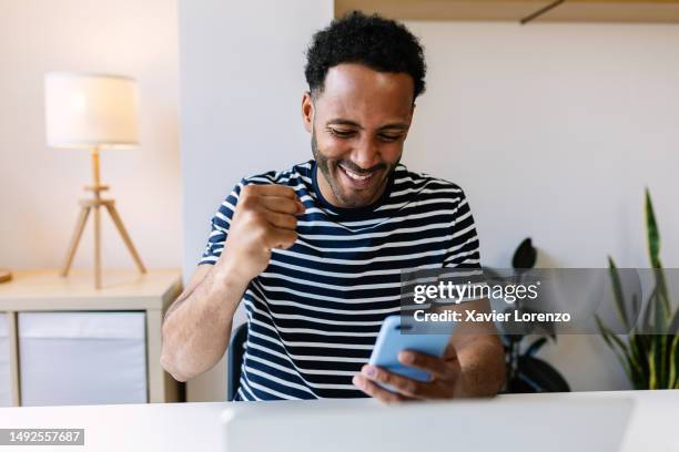 excited young african american man winning on internet lottery betting online on smartphone app. millennial guy celebrating victory enjoying success sports bet on cellphone. - jeux photos et images de collection