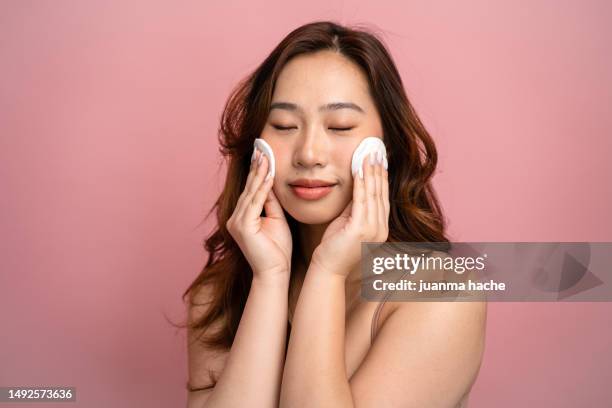 woman with two cotton pads on her face. - facial cleanser stockfoto's en -beelden