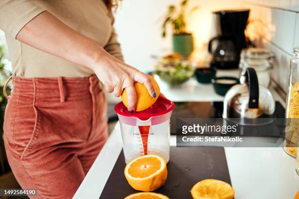woman's hands squeezing oranges in a juicer - woman squeezing orange stockfoto's en -beelden