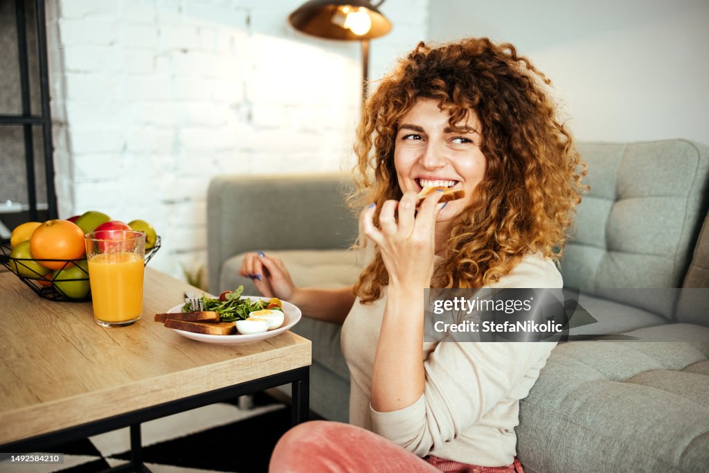 La mujer está desayunando en la sala de estar