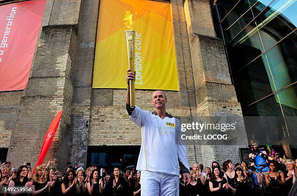 In this handout image provided by LOCOG, Torchbearer 001 Sir Clive Woodward holds the Olympic Flame at the Camden Roundhouse in Camden at the...