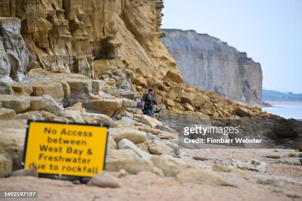 Person walks on the beach under the unstable East Cliff, following a substantial cliff fall on Sunday, on May 23, 2023 in West Bay, England.