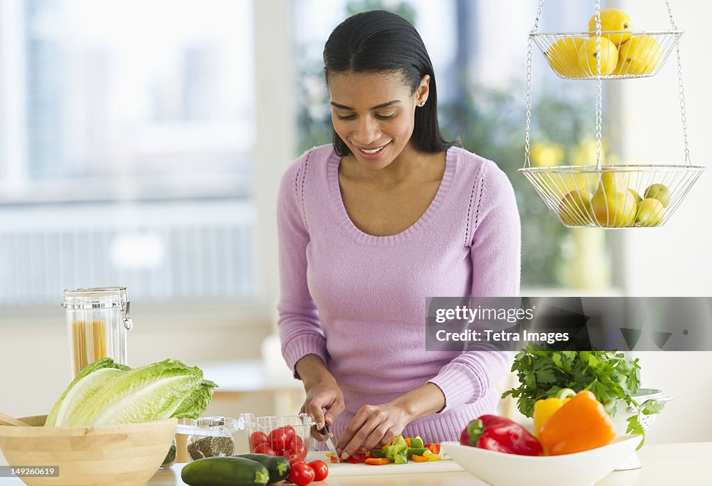 USA, New Jersey, Jersey City, Woman chopping vegetables in kitchen