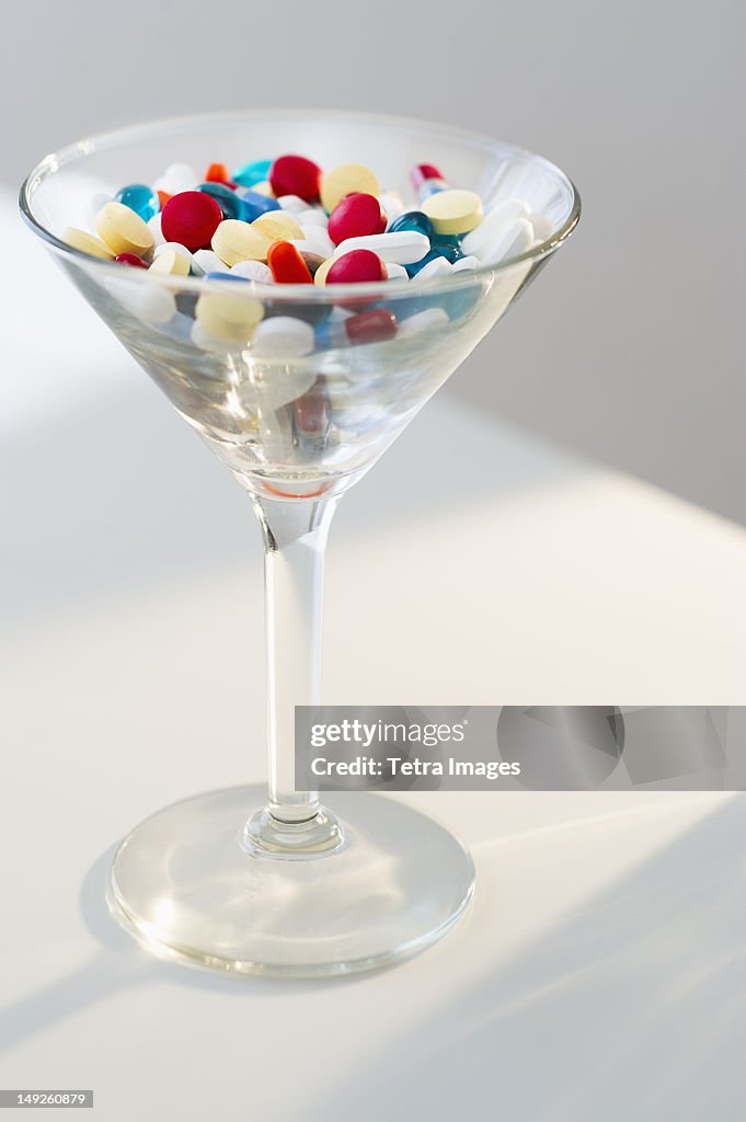 Martini glass filled with pills, studio shot