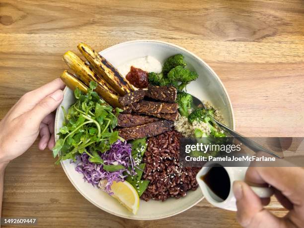 multiracial woman pouring salad dressing over rice, tempe, salad - molho vinagrete imagens e fotografias de stock