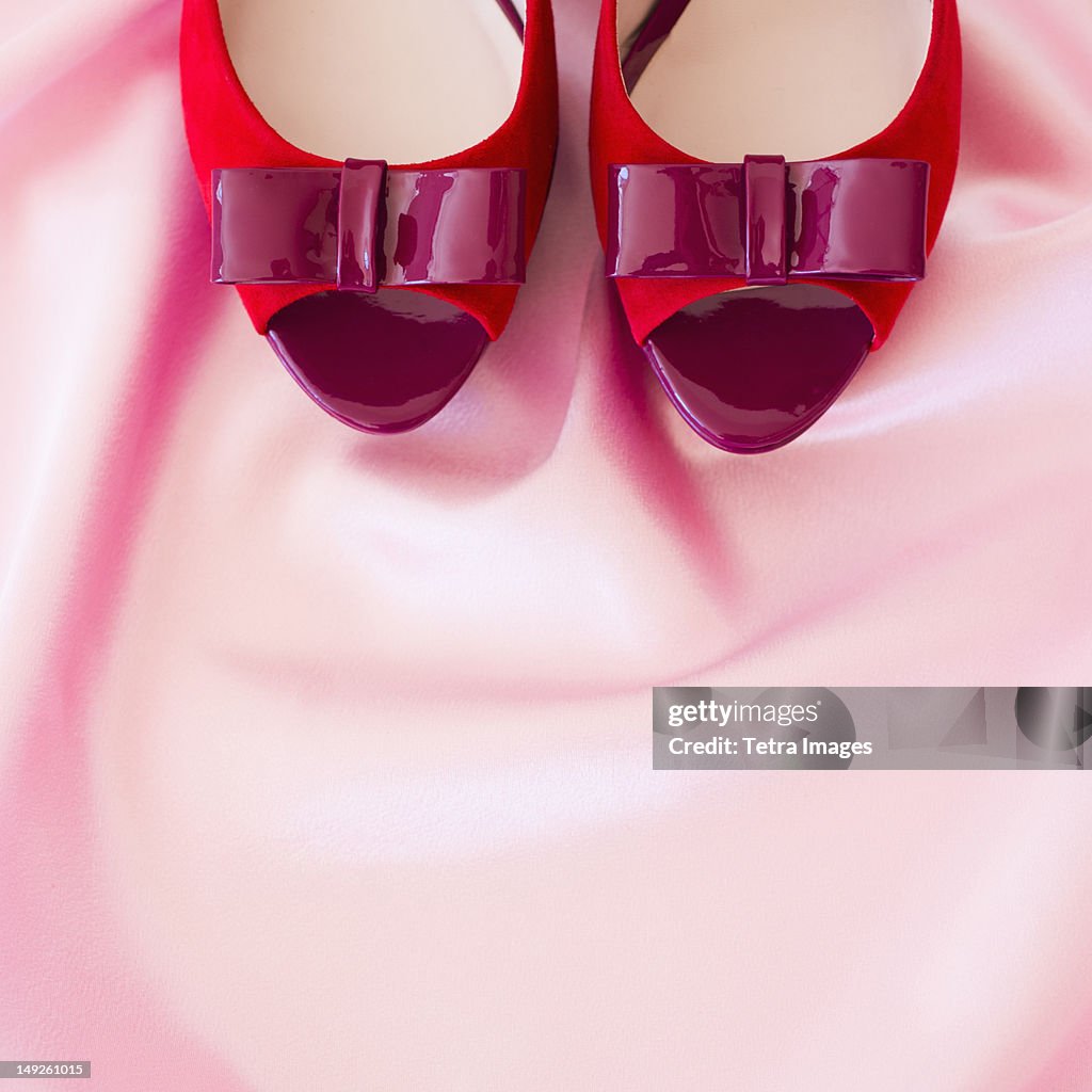 Pair of red high heel open toe shoes on pink textile