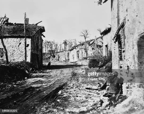 American troops creeping forward alongside ruined buildings during the First World War, with a German machine gun nest in the trees overlooking the...