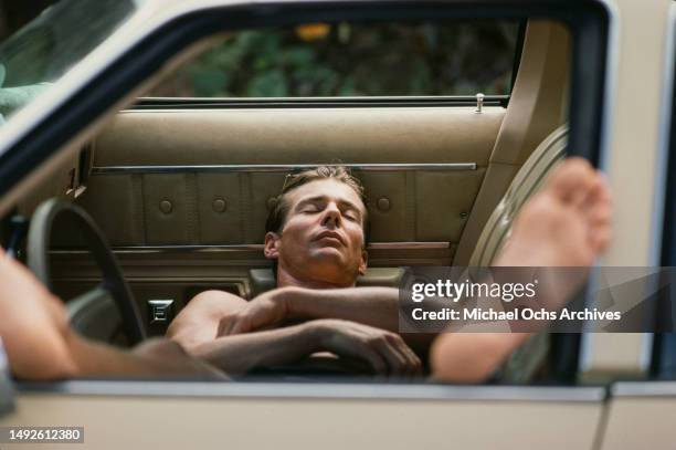 American actor Jan-Michael Vincent relaxing in a car between takes on the set of 'Big Wednesday', at Sunset Beach, on the north shore of Oahu ,...