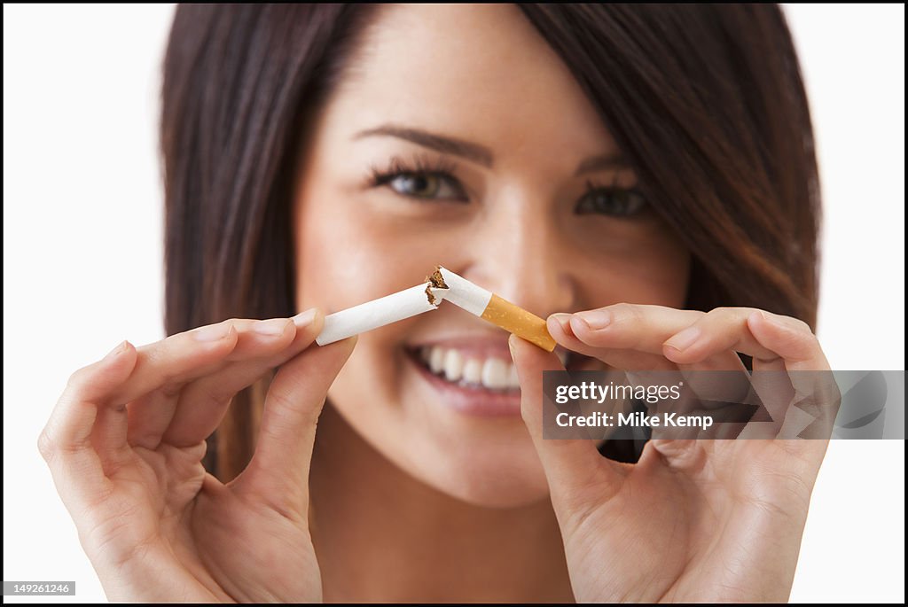 Young woman breaking cigarette