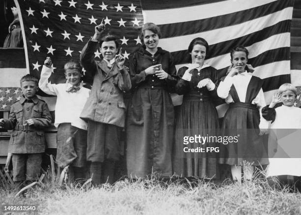 Children using sign language to sing the US national anthem, 'The Star Spangled Banner', standing before the flag of America, at the St Rita School...