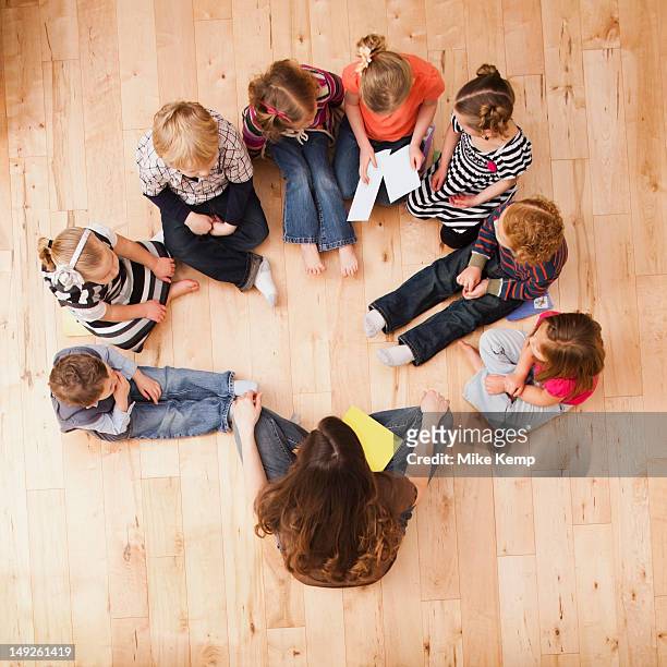 children (2-3, 4-5) sitting in circle around teacher, directly above - bambini seduti in cerchio foto e immagini stock
