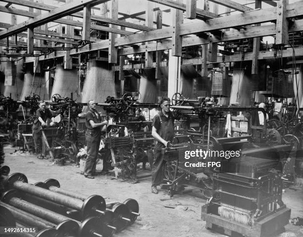 Men operating Jacquard looms during the manufacture of tapestries in an unspecified textile mill, location unspecified, United States, circa 1935. A...