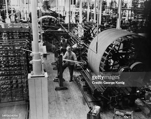 Man operates warping machinery at the Wilson & Glenny mill in Hawick, Scotland, 8th August 1949. Warping is the process through which fibres are...