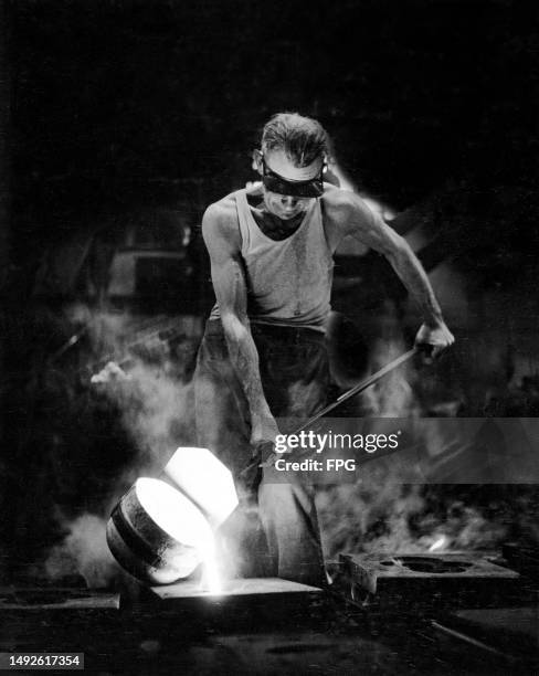 Foundry worker uses a foundry ladle to pour metal into a mold for a lamp base, at the Union Metal Company foundry in Canton, Ohio, circa 1955.