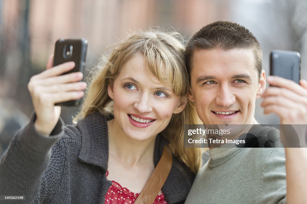 USA, New Jersey, Jersey City, Couple photographing themselves with smart phones