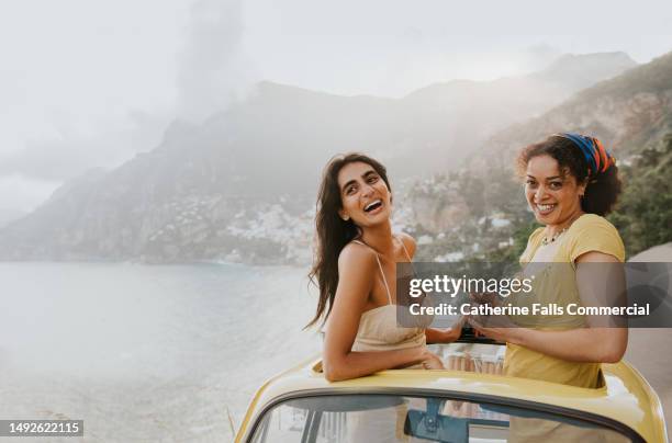 two woman enjoy experiential travel in a rented vintage car in italy - indian tour guide stock pictures, royalty-free photos & images
