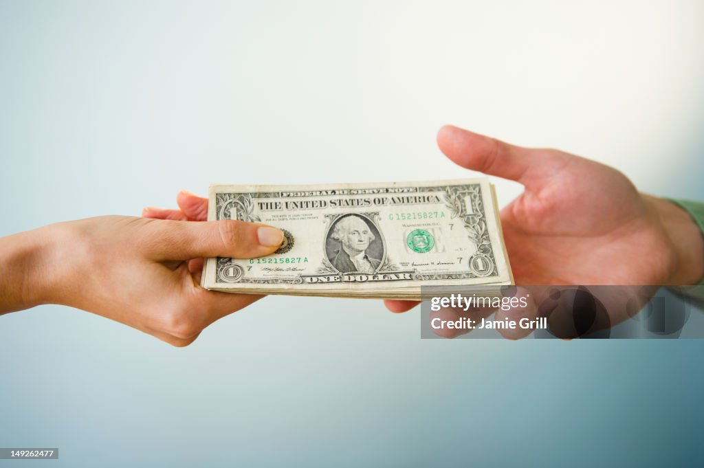 Close up of man's and woman's hands holding banknotes, studio shot