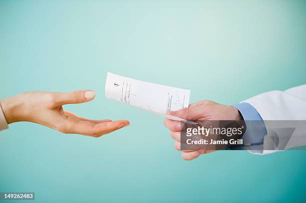 close up of doctor's hand giving prescription to patient, studio shot - prescription medicine stock pictures, royalty-free photos & images
