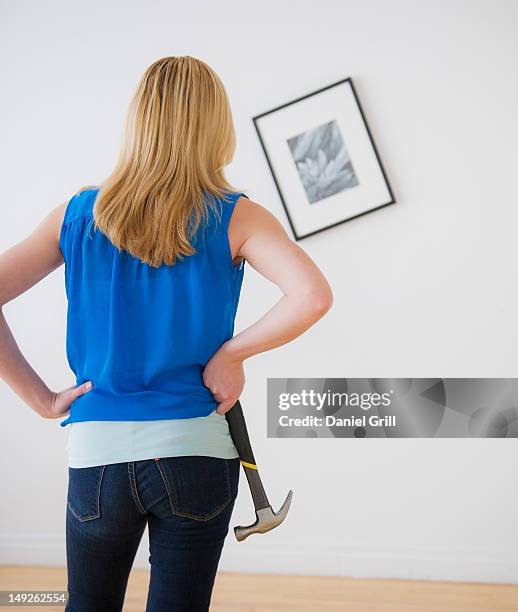 rear view of woman holding hammer and looking at painting on wall - draped fotografías e imágenes de stock