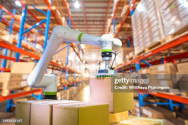 automated robot carriers and robotic arm in smart distribution warehouse - automatic stock pictures, royalty-free photos & images