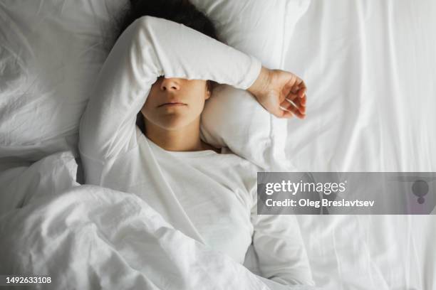 woman lying down in bed and crying with closed face. relationship breakup and stress - midlife crisis stock pictures, royalty-free photos & images