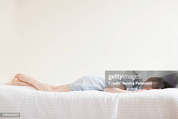 attractive young woman sleeping in bed - allongé sur le devant photos et images de collection