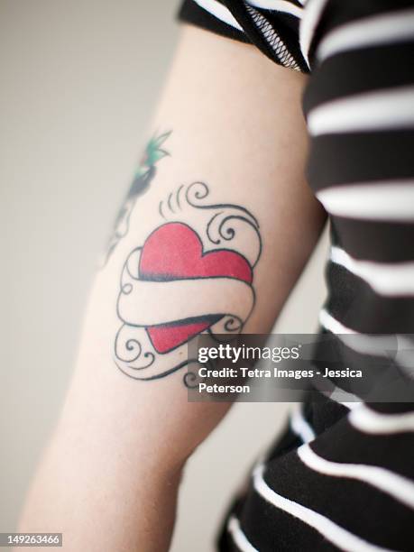 heart shaped tattoo on woman's arm - tatouage stockfoto's en -beelden