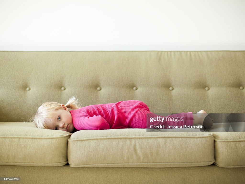 Portrait of baby girl (18-23 months) resting on sofa