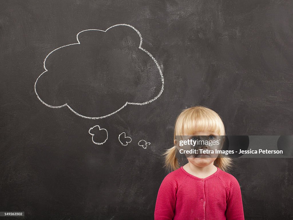 Portrait of baby girl (18-23 months) in front of blackboard