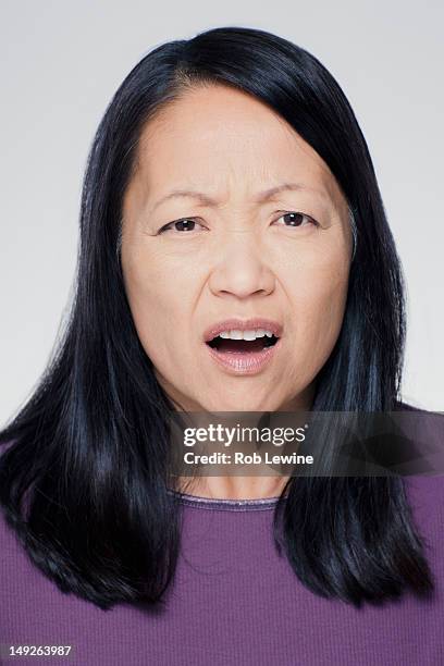 studio portrait of mature woman with facial expression - asian woman angry foto e immagini stock