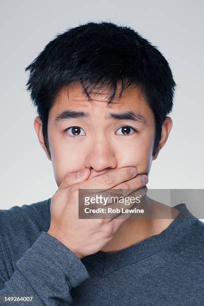 studio portrait of young man covering mouth - vomiting stock pictures, royalty-free photos & images