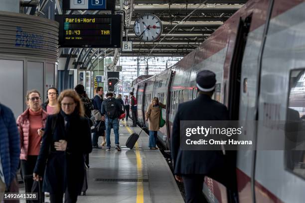Passenger boards a Thalys train bound for Paris-Nord at Gare Du Midi station while others arriving on the same train walk towards the station exit on...