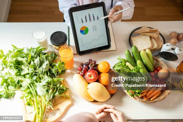 detox-konzept. afro-patientin des ernährungsberaters, die zitronenwasser trinkt, während der arzt notizen macht, nahaufnahme - culinary stock-fotos und bilder