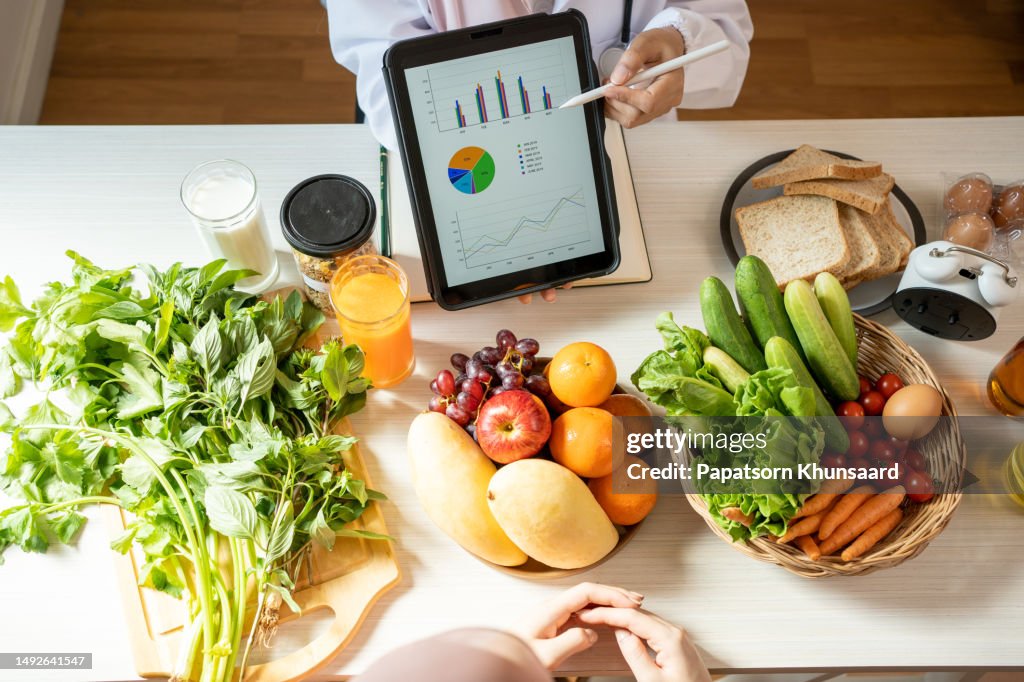 Concepto detox. Mujer afro paciente de nutricionista bebiendo agua de limón mientras el médico toma notas, de cerca