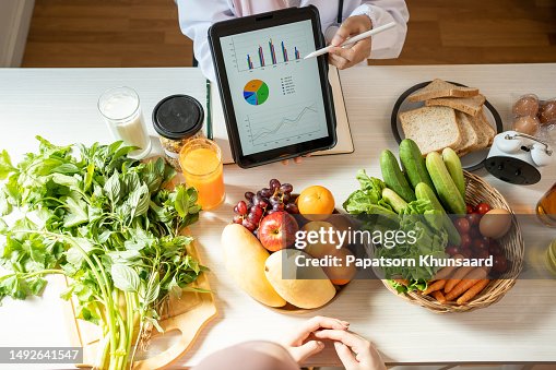 Detox concept. Afro woman patient of nutritionist drinking lemon water while doctor taking notes, close up Detox concept. Afro woman patient of nutritionist drinking lemon water while doctor taking notes, close up