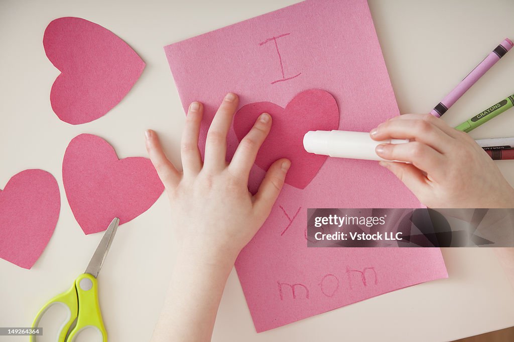 Girl (4-5) preparing greeting card for mother