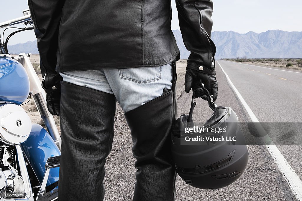 USA, Illinois, Metamora, Biker on road holding crash helmet