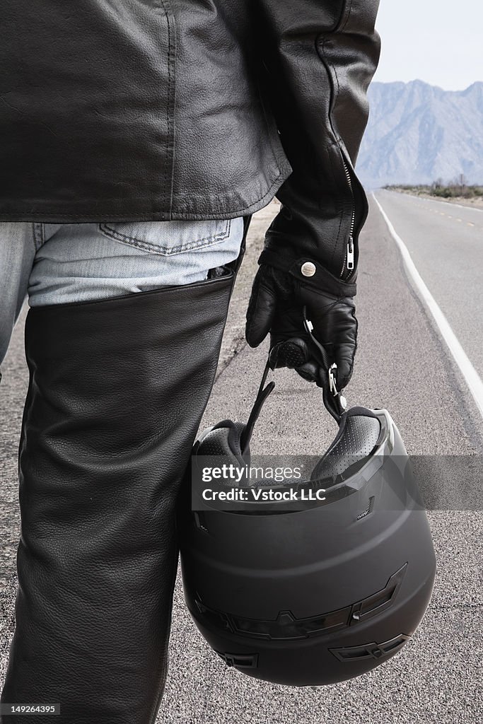 USA, Illinois, Metamora, Biker on road holding crash helmet
