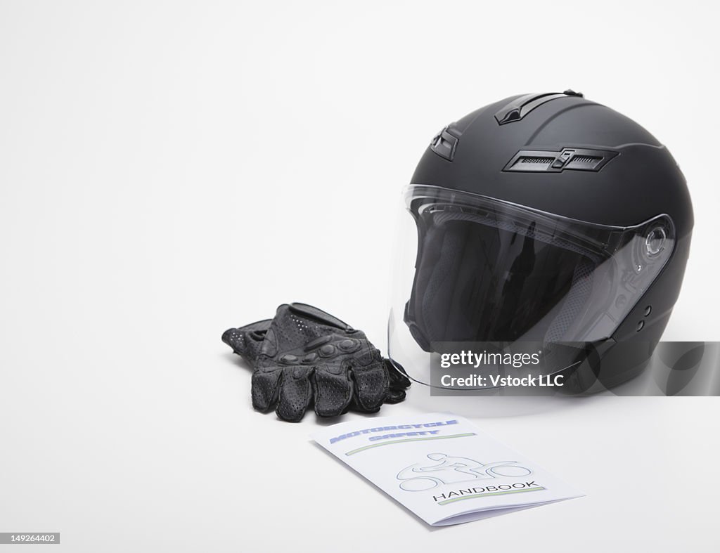 Studio shot of crash helmet, gloves and safety guide