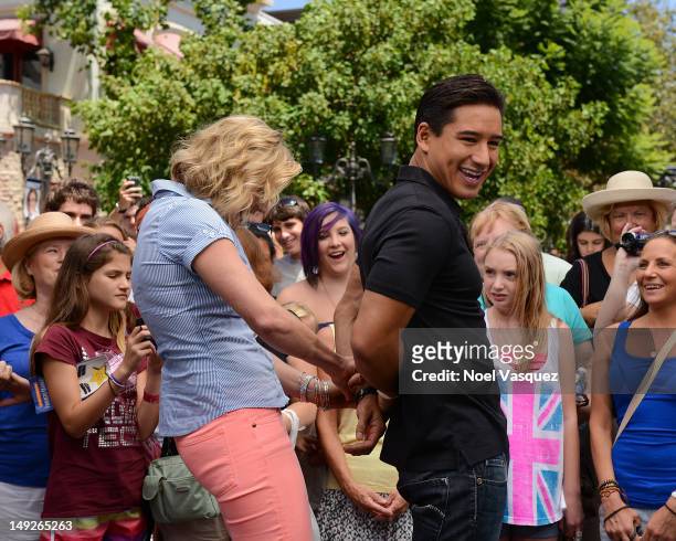 Katee Sackoff attempts to place handcuffs on Mario Lopez at "Extra" at The Grove on July 25, 2012 in Los Angeles, California.